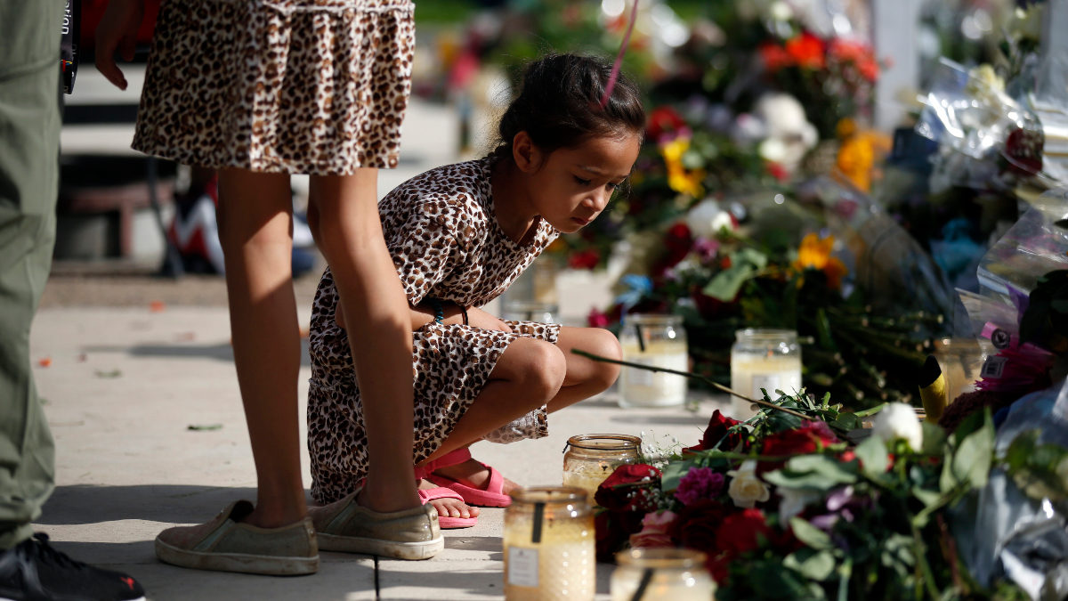 A girl lights a candle at a memorial to victims of the 2022 Robb Elementary shooting in Uvalde, Texas.