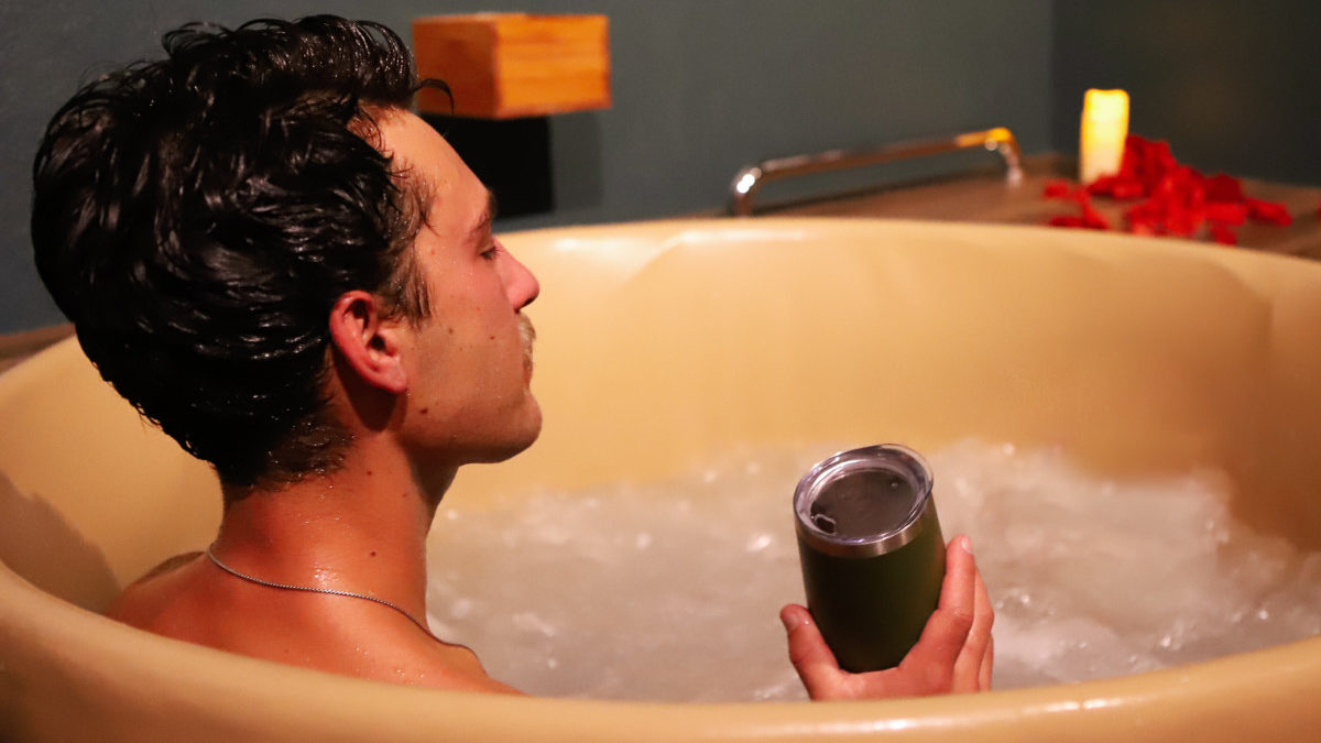 A man soaks in a tub of beer, while holding a drink at The Beer Spa in Denver.