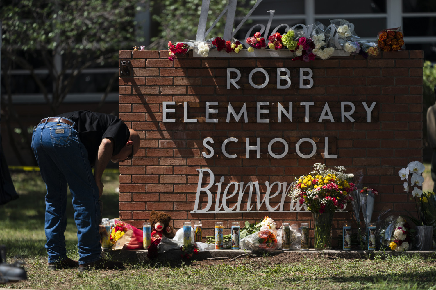 A mourner pays tribute before the sign outside Robb Elementary School in Uvalde, Texas.