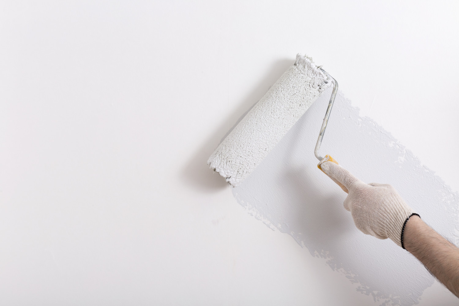 Close up of painter arm painting a wall with paint roller