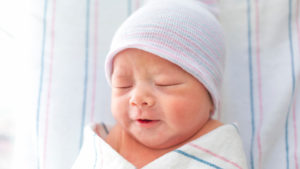 Infant swaddled and wearing hat