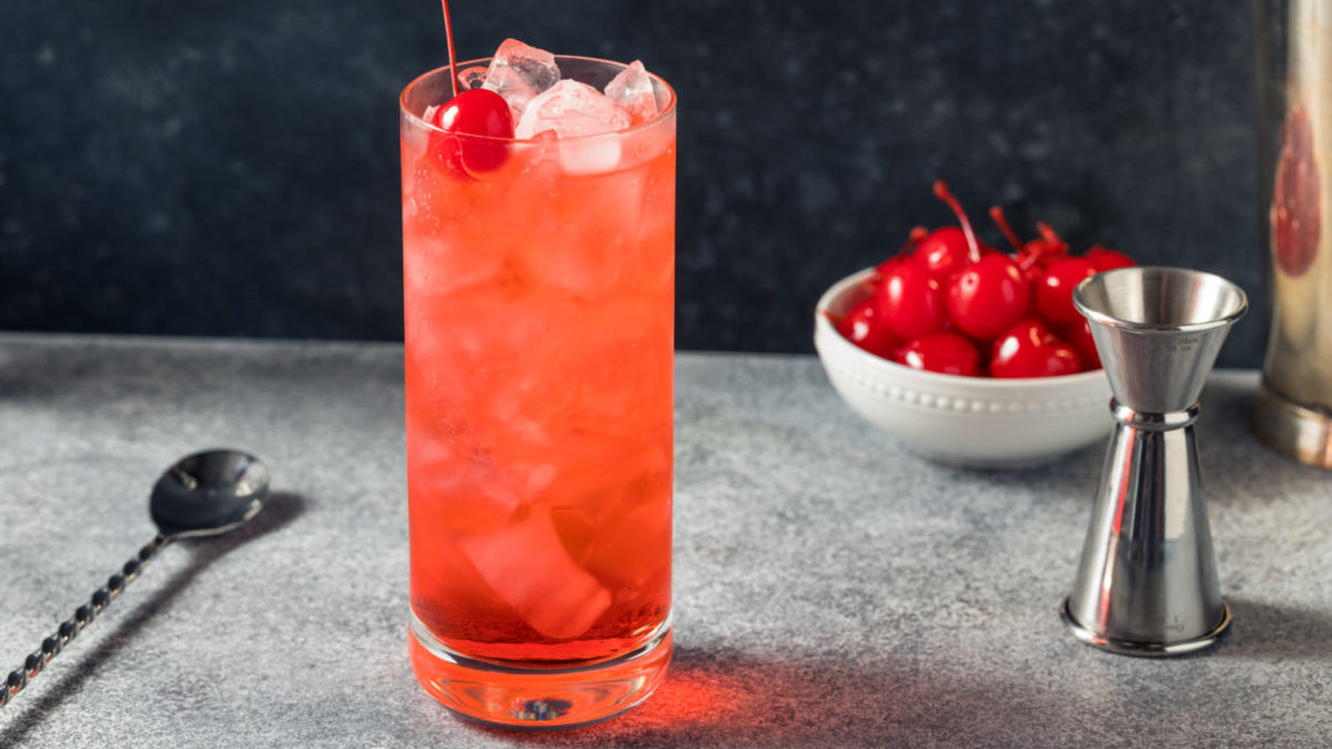 A Dirty Shirley cocktail is shown with a bowl of cherries.