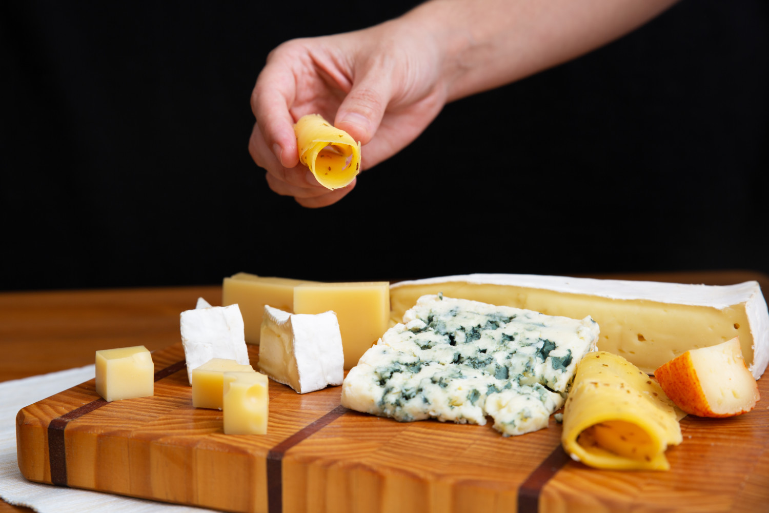 Hand takes cheese from board