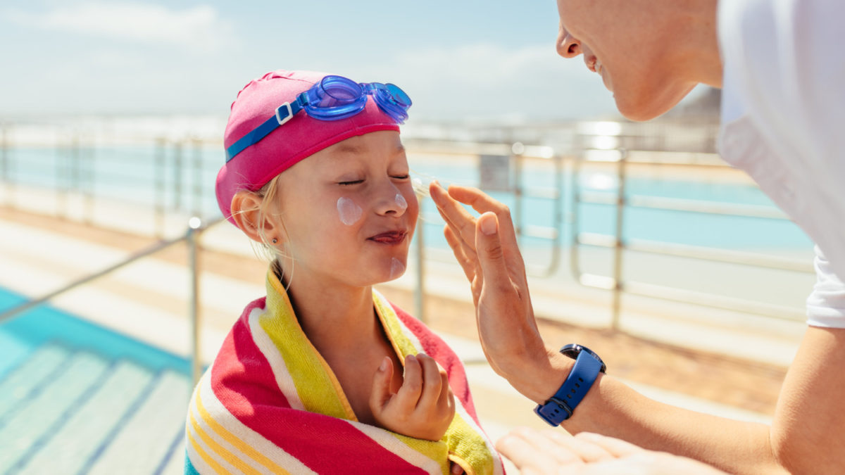 A little girl gets skin barrier cream put on before swimming.