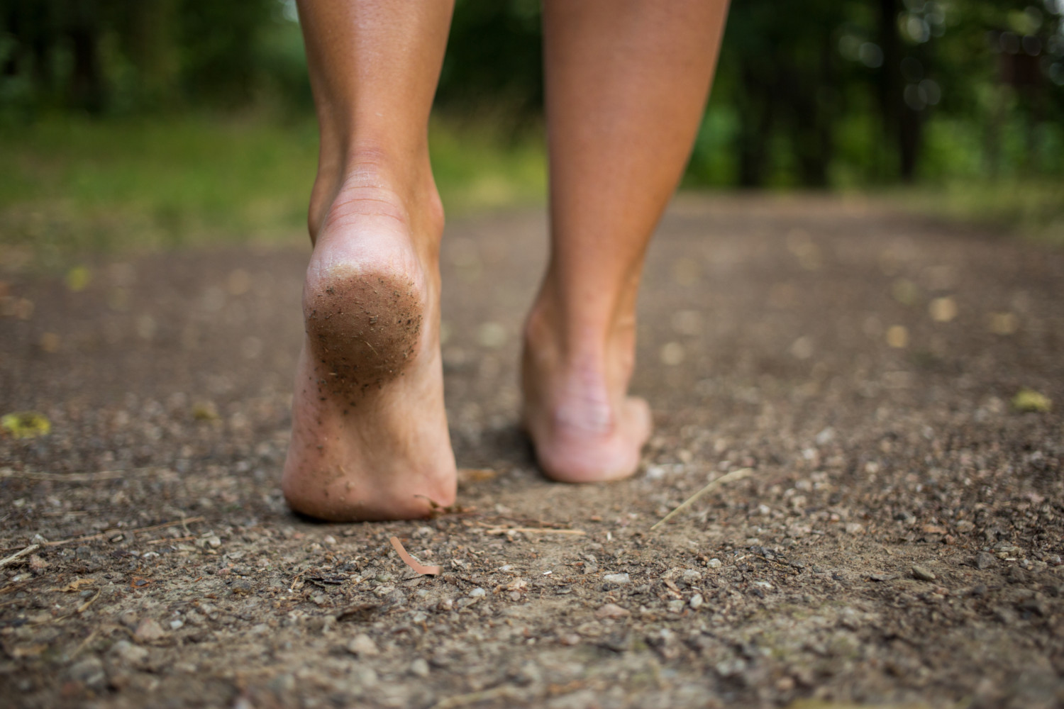 person’s feet shown walking on dirt road