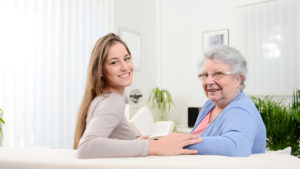 Young woman and senior woman sit on couch together
