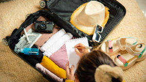 A woman packs her suitcase for a trip, checking a list as she goes.