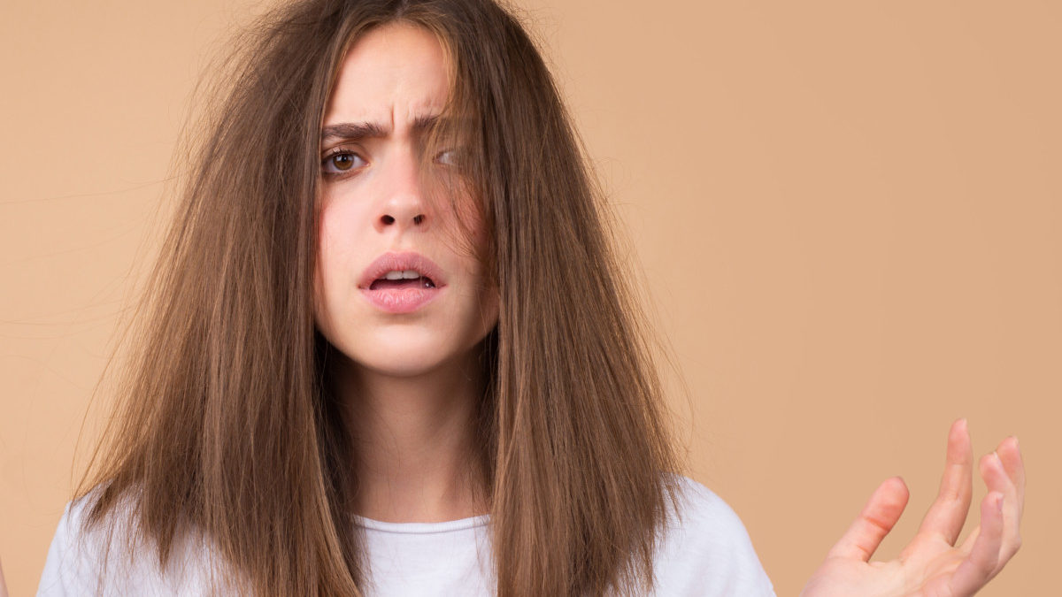 A woman with frizzy brown hair looks frustrated.