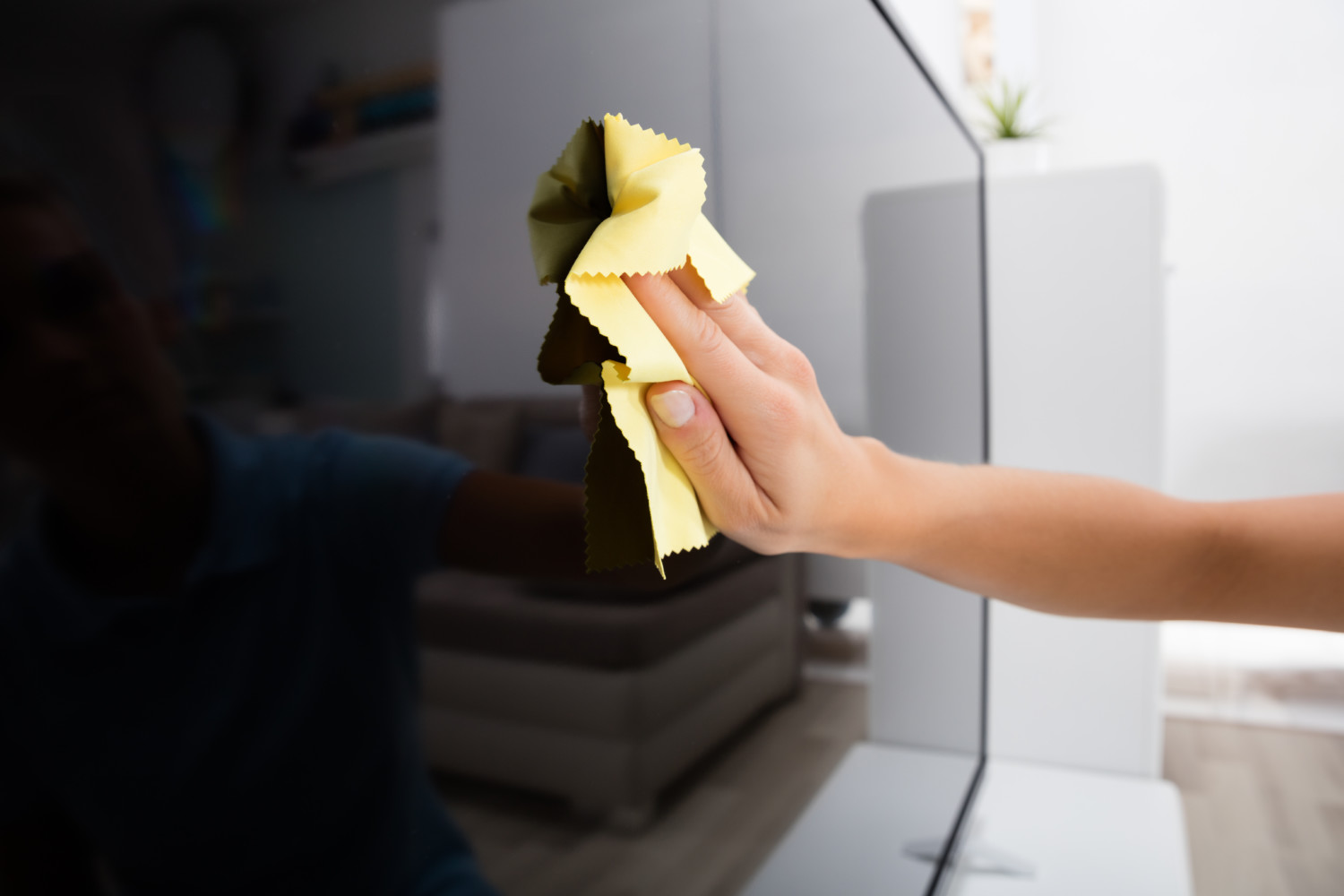 Woman Using Cloth To Clean The Television