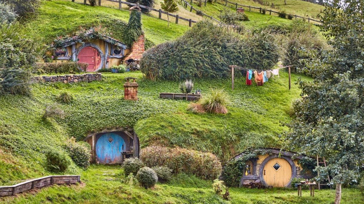 Hobbit houses build into a New Zealand hillside are shown.
