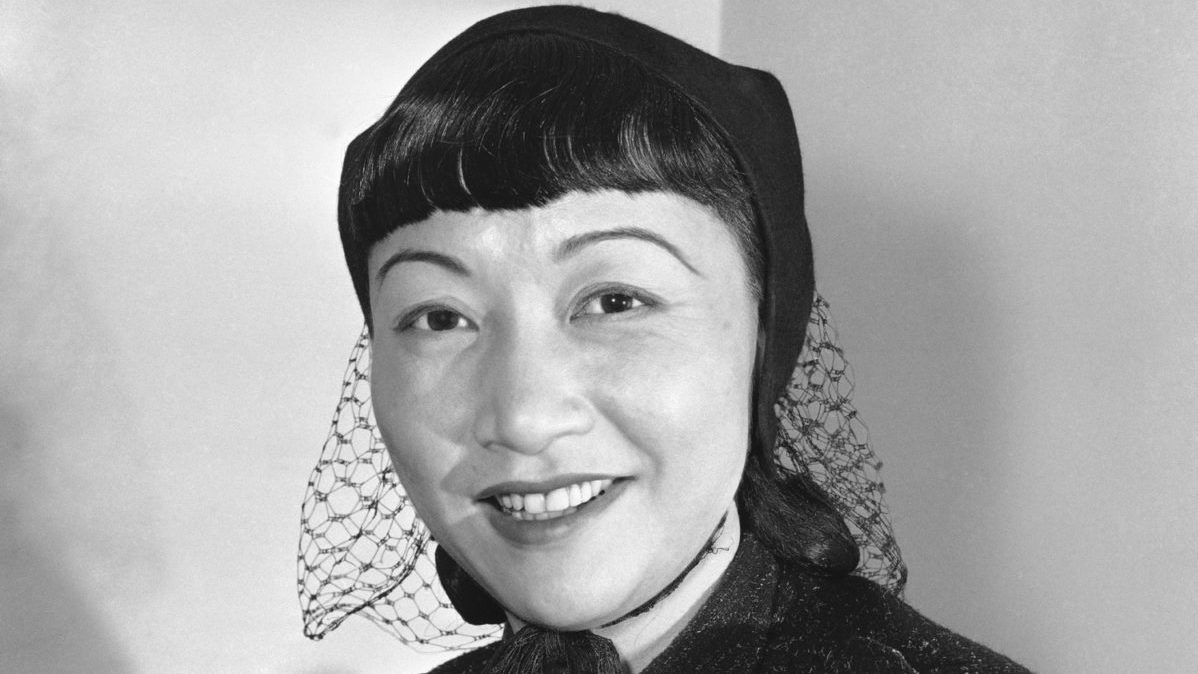Anna May Wong smiles in a black and white photograph.