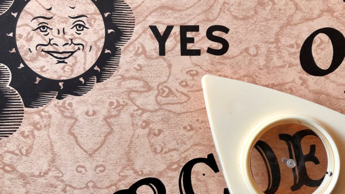 A Ouija board and planchette are shown in close-up.
