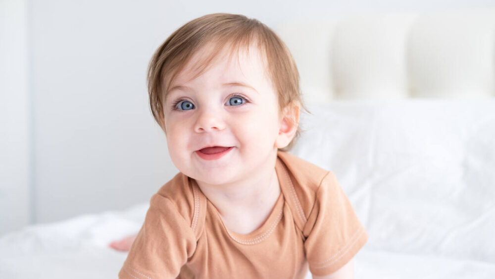 baby with blue eyes crawls on bed