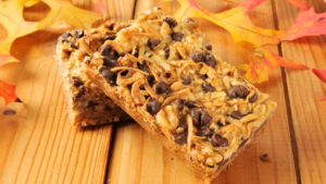 A few Hello Dollies, aka 7-Layer Bars, are shown on a fall-themed surface.