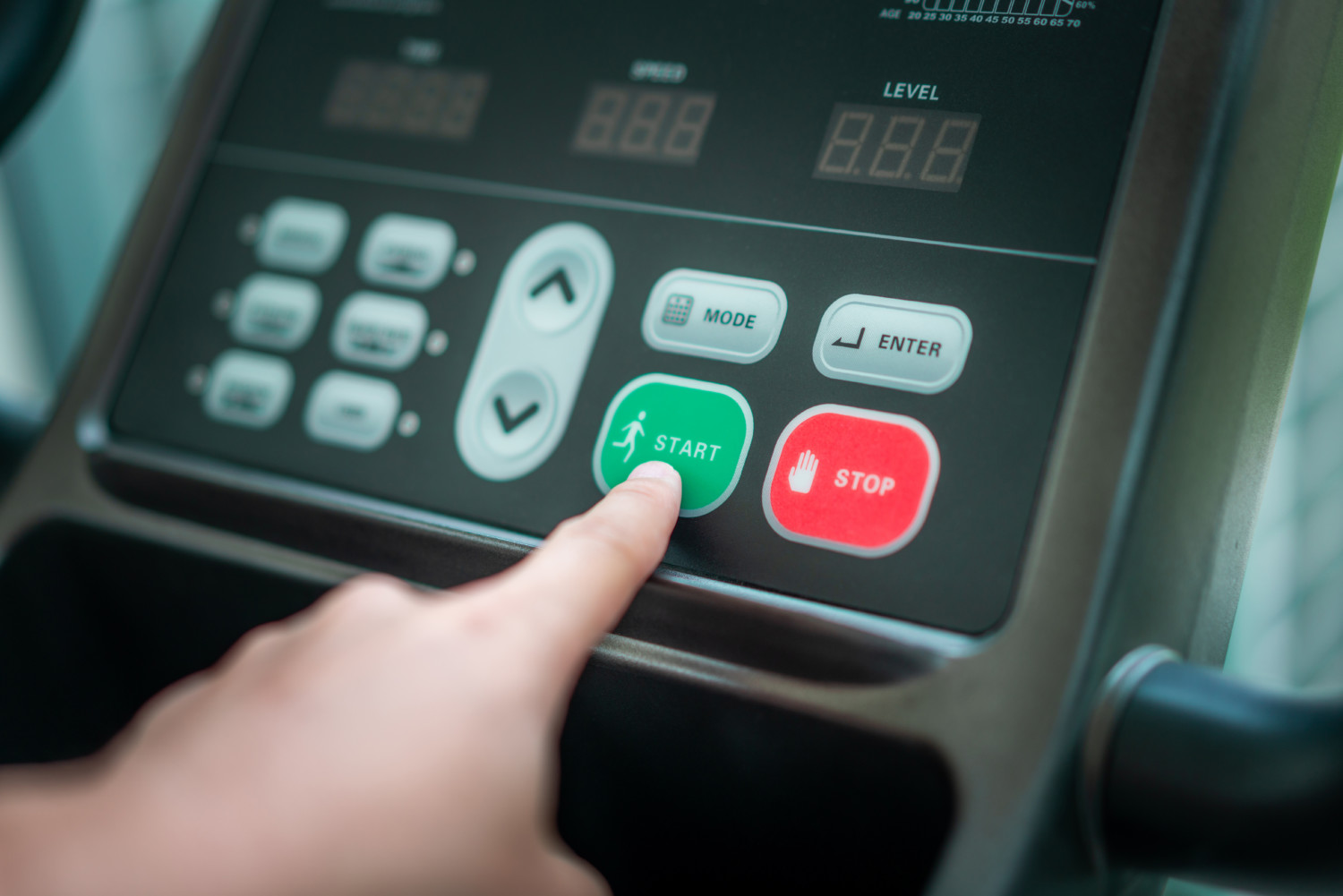 Hand pressing start button on treadmill control panel