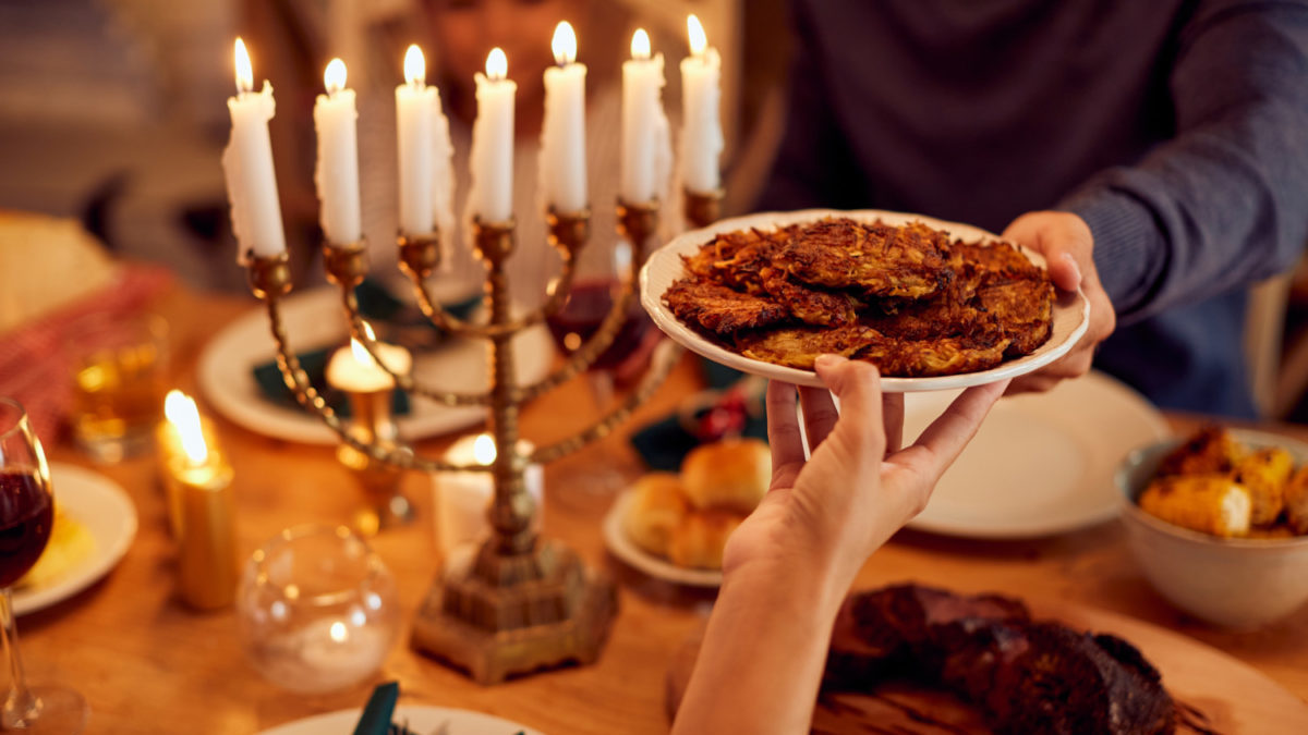 A plate of latkes is passed across a Hanukkah table.