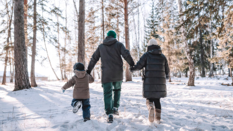 Family holds hands on snowy winter walk
