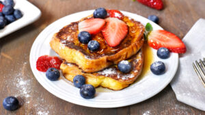 French toast with berries on white plate
