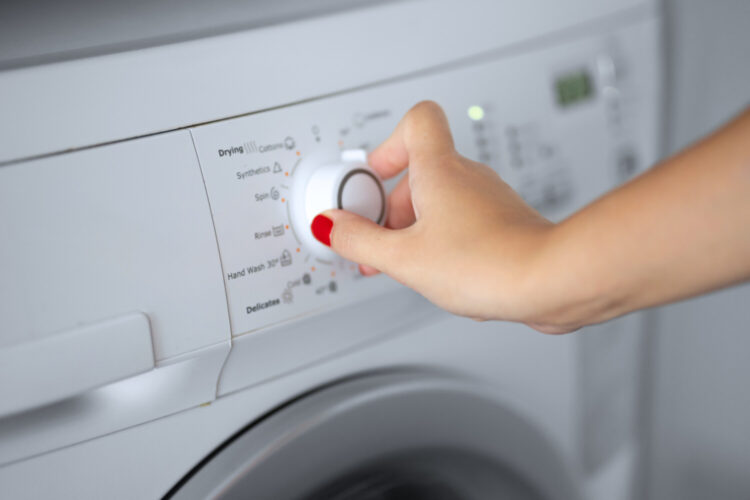 woman turning washing machine dial