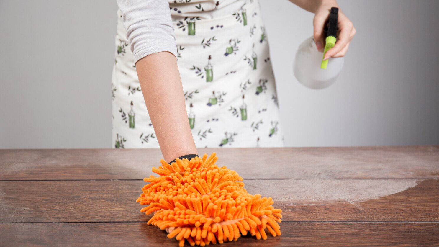 Woman dusts table with duster and spray