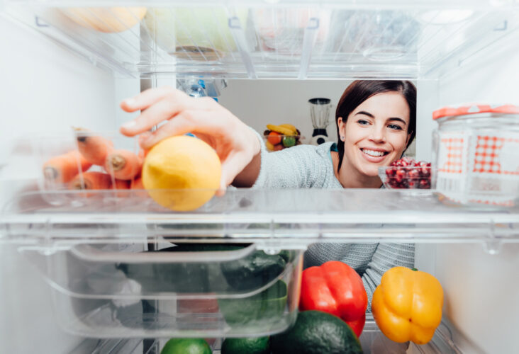 Woman reaches for food in refrigerator