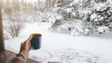 Holding mug with tea over snowy view