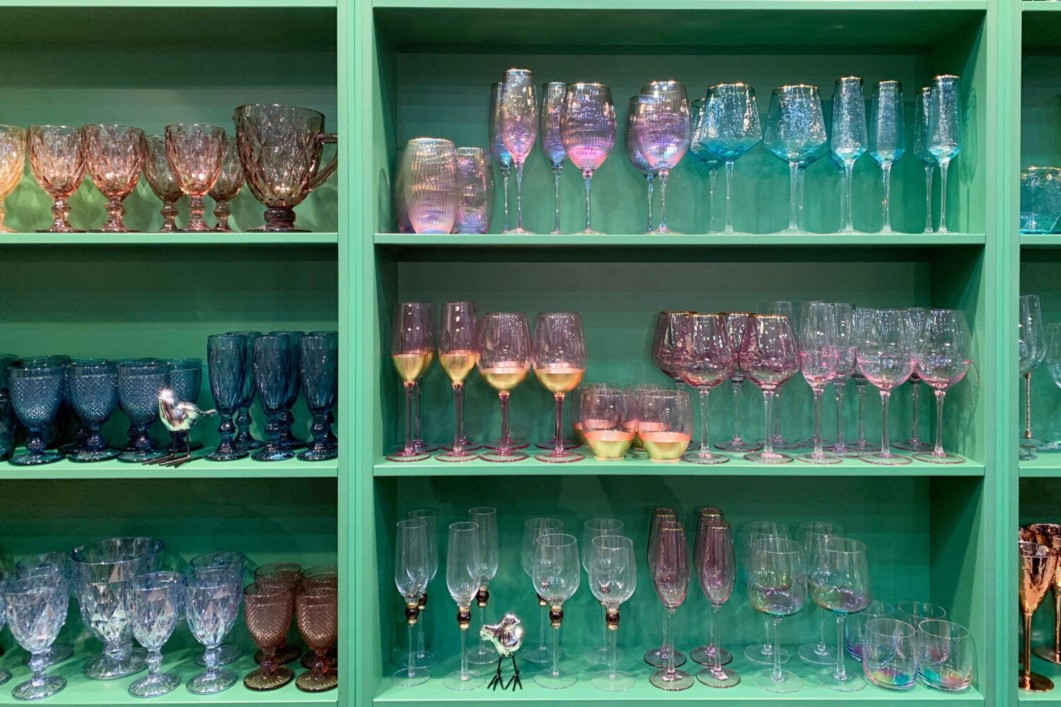 Colorful glassware on green cabinet shelves