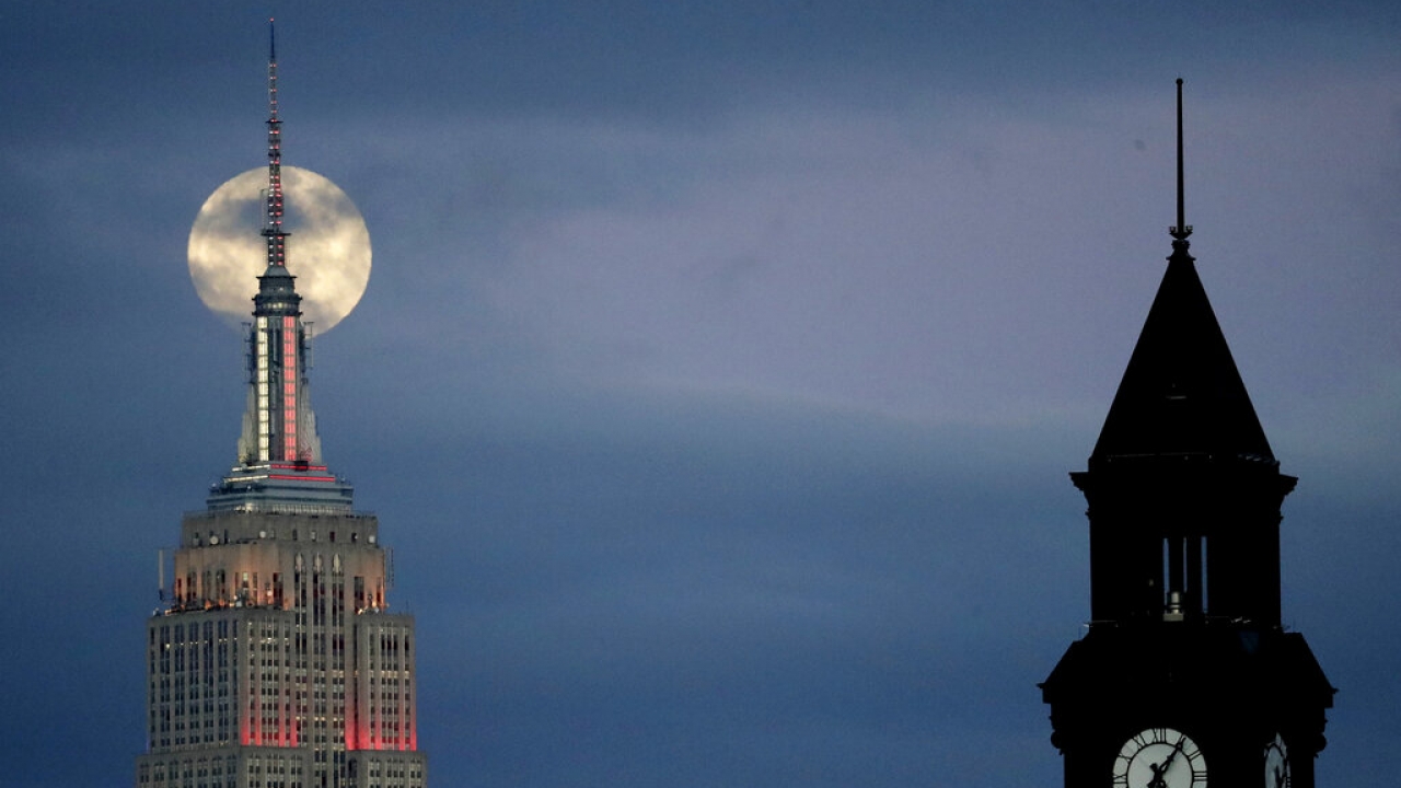 Full moon shows behind Empire State Building in New York