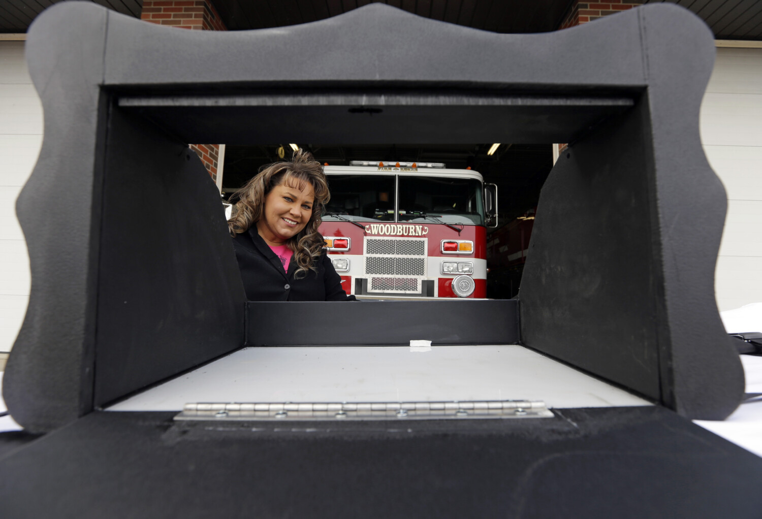 Monica Kelsey, firefighter and medic who is president of Safe Haven Baby Boxes Inc., poses with a prototype of a baby box, where parents could surrender their newborns anonymously, outside her fire station in Woodburn, Ind., Thursday, Feb. 26, 2015. The box is actually a newborn incubator, or baby box, and it could be showing up soon at Indiana hospitals, fire stations, churches and other selected sites under legislation that would give mothers in crisis a way to surrender their children safely and anonymously. (AP Photo/Michael Conroy)