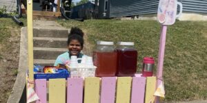 Naivy Bloxson sits at her lemonade stand