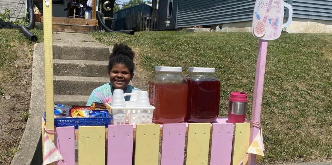 Naivy Bloxson sits at her lemonade stand