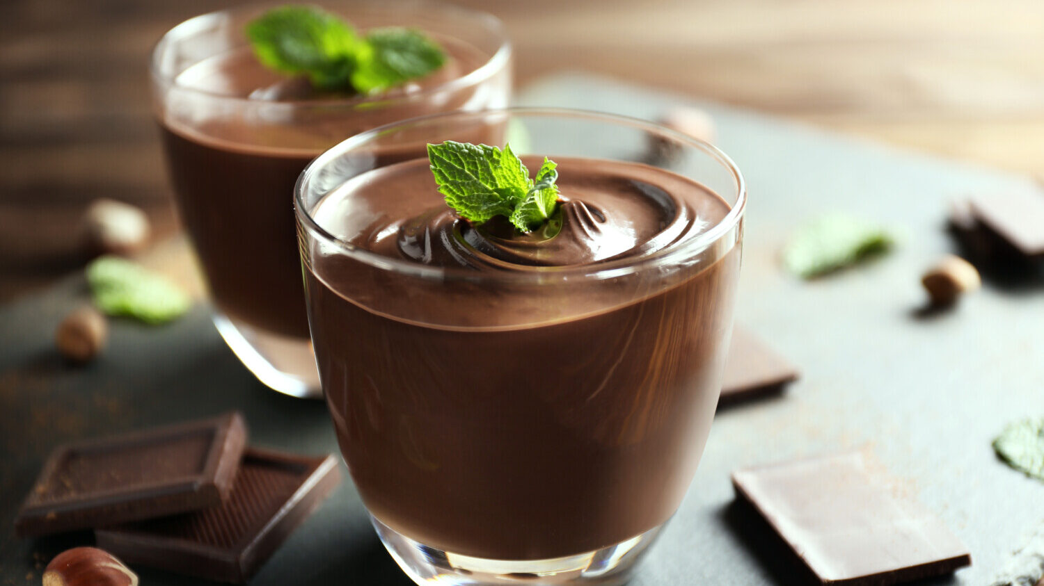 photo of chocolate mousse served in glass cup with mint garnish