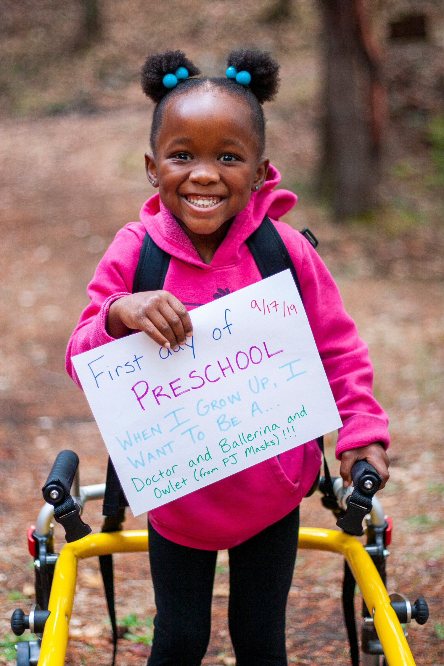 Girl holds "first day of preschool" sign in portrait