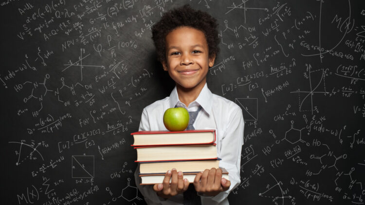 Back to school portrait of boy holding books, apple