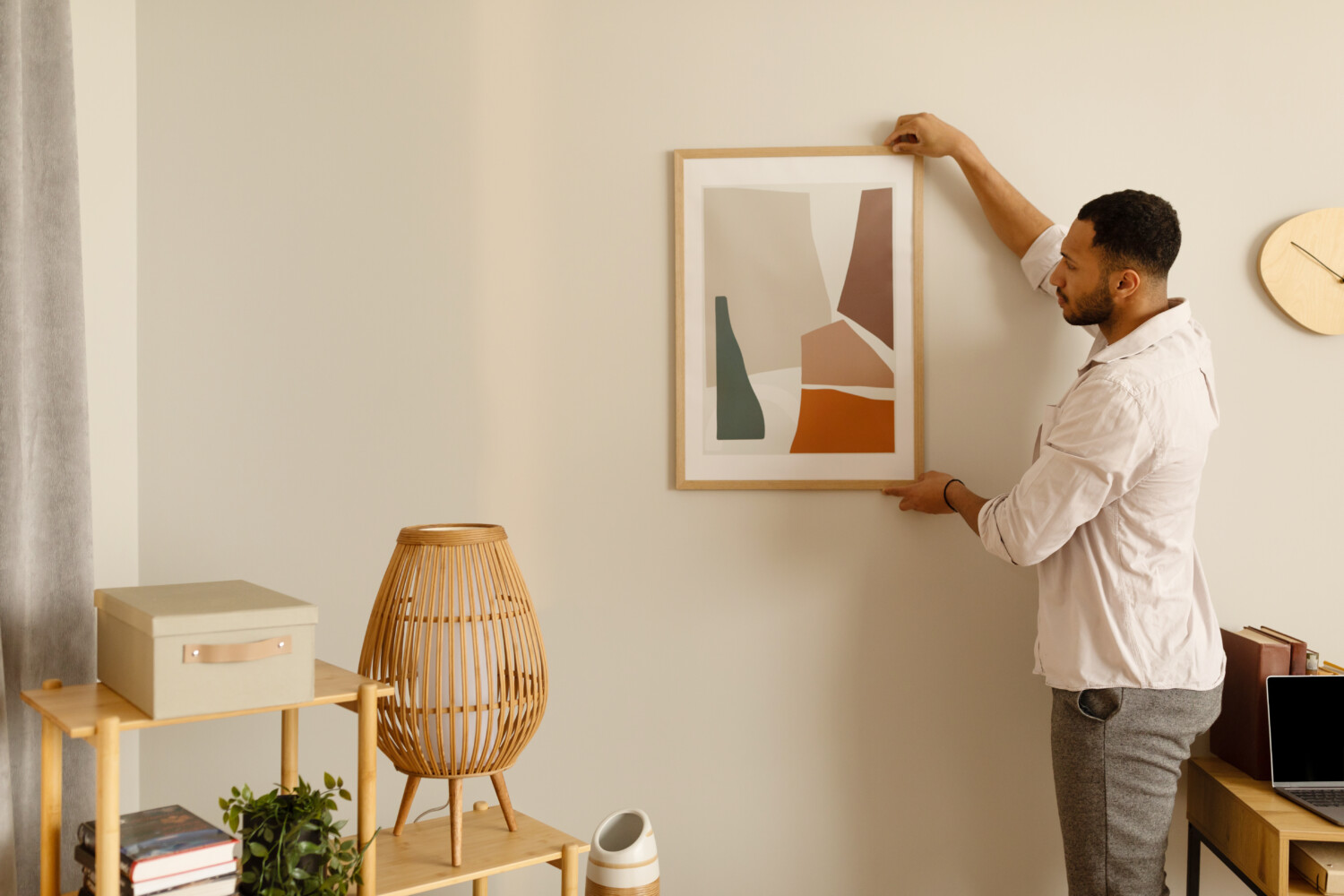 Man hangs artwork on wall in his home