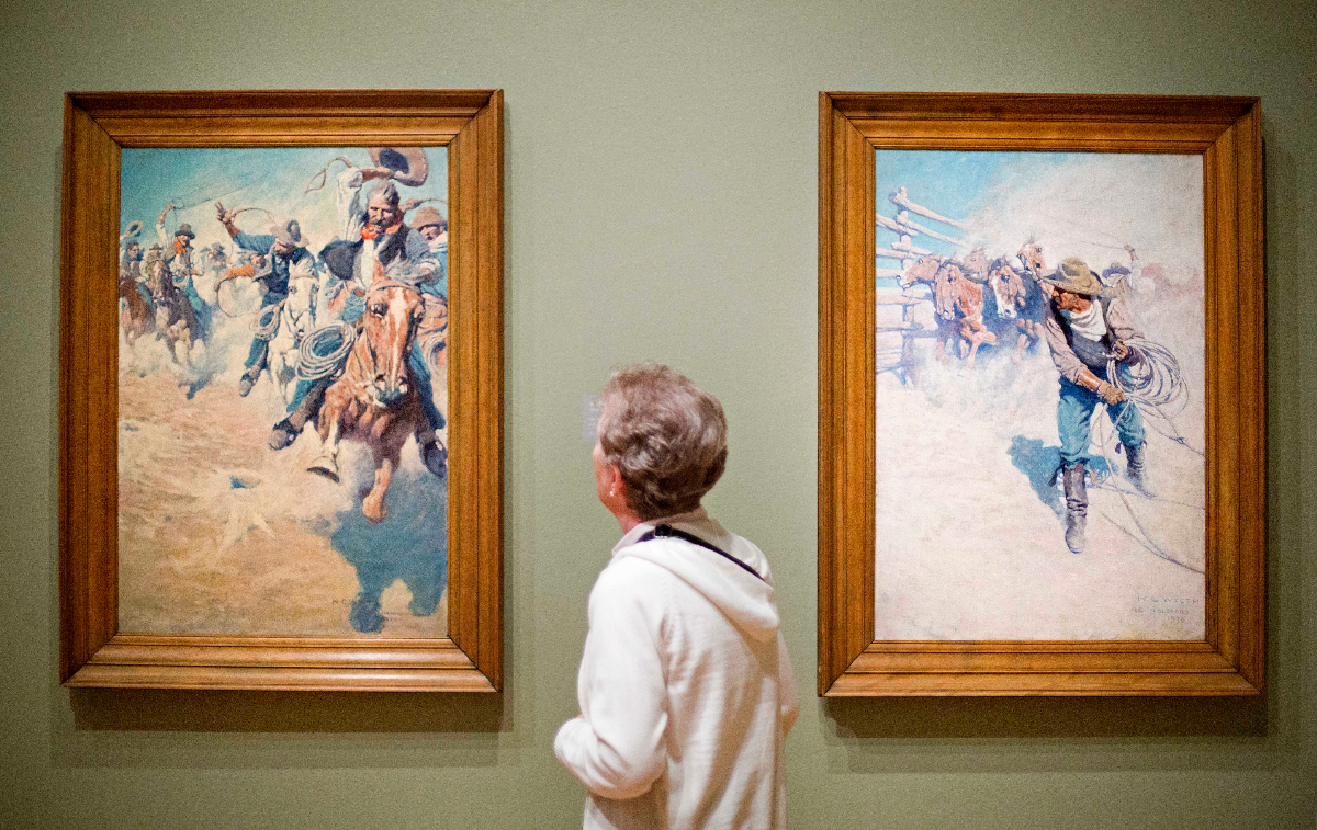 Exhibit visitor looks at Oil on canvas paintings by N.C. Wyeth