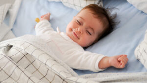 Smiling baby lying on a bed sleeping on blue sheets