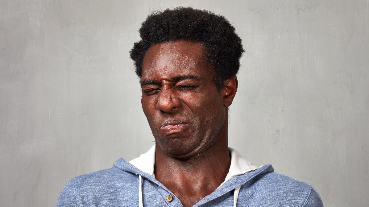 Black man disgust face expressions portrait over gray background.