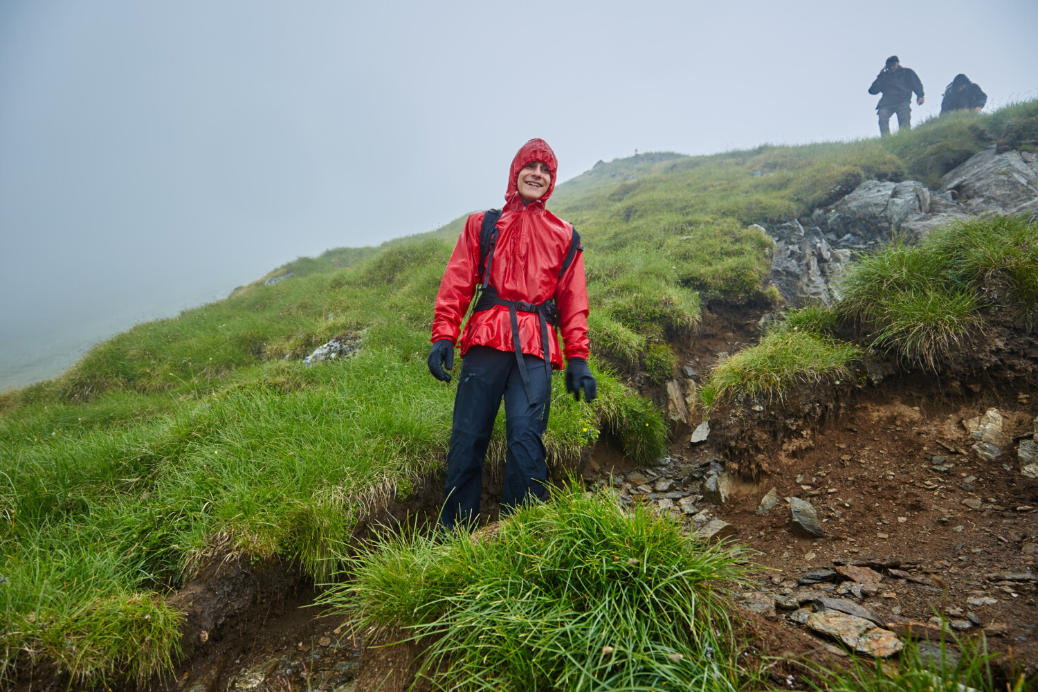 Hiker in raincoat smiles in bad weather