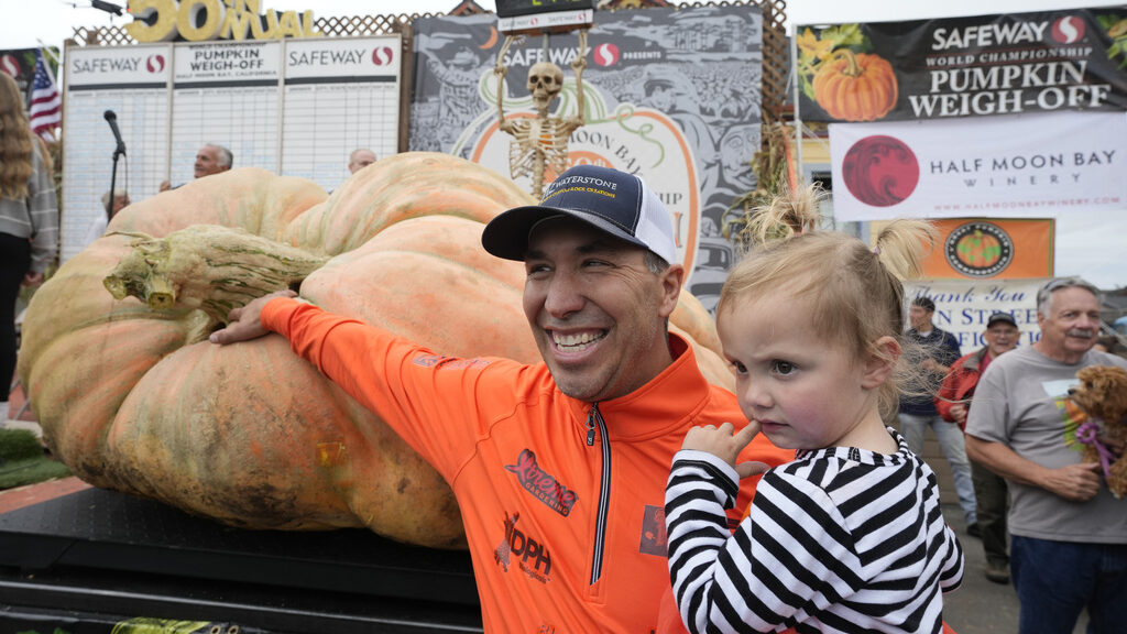 Travis Gienger and daughter Lily pose by his record-setting pumpkin