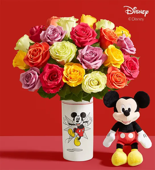 brightly colored roses in mickey mouse planter with plush mickey mouse sitting next to it 