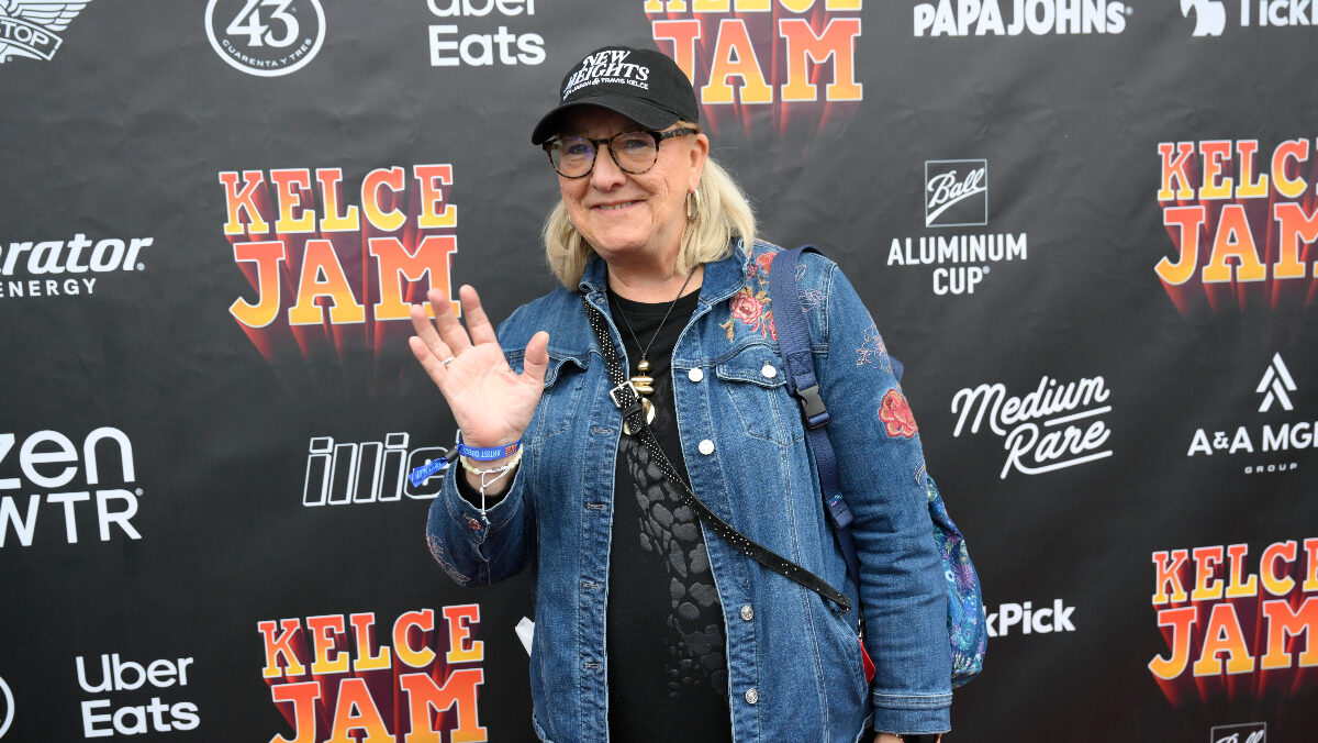 Donna Kelce wearing a denim jacket in front of a step and repeat banner that reads "Kelce Jam"
