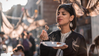 Female tourist in Paris France enjoying a plate of food outdoors at a market
