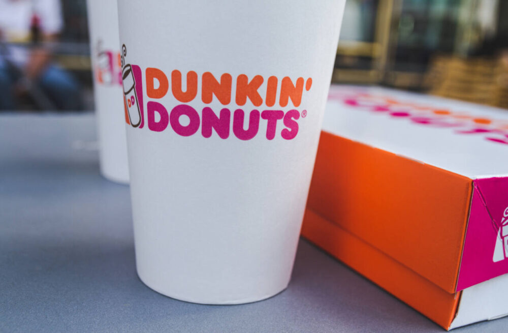 Dunkin' Donuts logo on a cup of coffee, next to packaging box with delicious doughnuts on August 11, 2018 in Berlin, Germany.