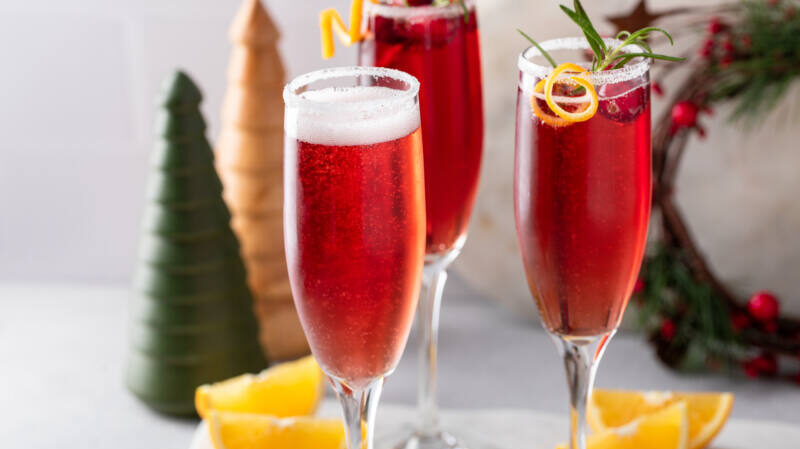 Cranberry fizzy drink in champagne flutes with holiday background