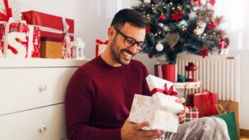 Man smiles while opening a Christmas gift