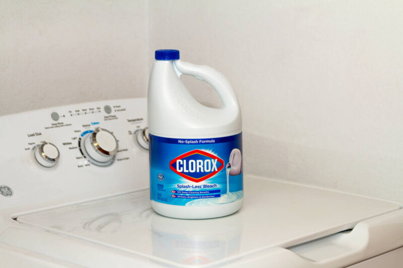 Bottle of bleach sits on top of washing machine