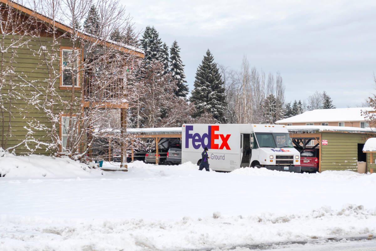 A FedEx driver walks through heavy snow to her truck after delivering packages to an apartment complex in winter on December 11 2020 in Coeur d'Alene, Idaho USA