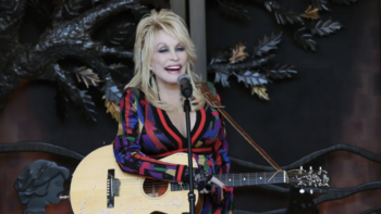 Dolly Parton holding a guitar in front of HeartSong Lodge & Resort