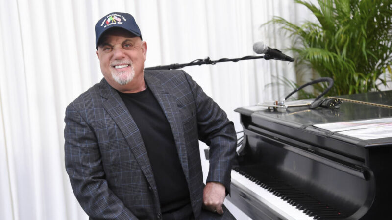 Billy Joel sits at a piano